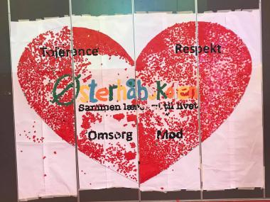 Billede af stort hjerte sammensat af mange småstykker papir med ordene tolerance, respekt, Østerhåbskolen, sammen lærer vi til livet, omsorg og mod.