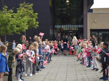 Børn med flag hilser nye elever velkommen til skolestart