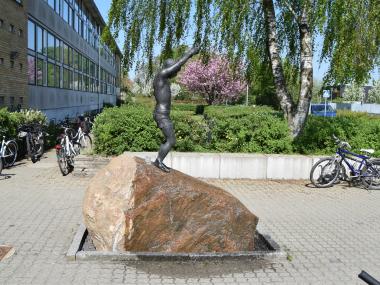Bronzefigur "Ud i livet" foran skolens indgang